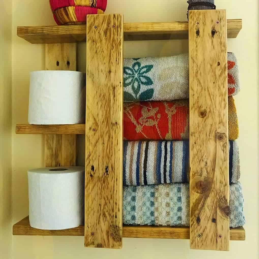 wood pallet plank bathroom wall shelf holding toilet paper and towels 