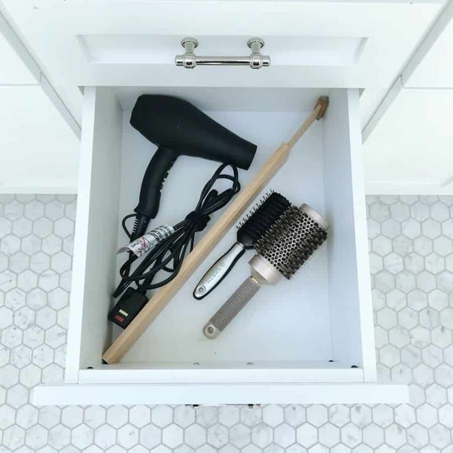 bathroom cabinet drawer with hair dryer and brushes