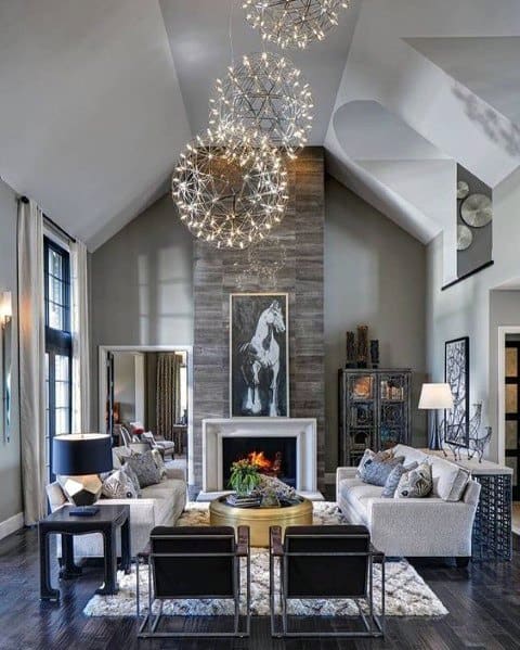 modern living room stone fireplace high ceilings chandelier gray couch