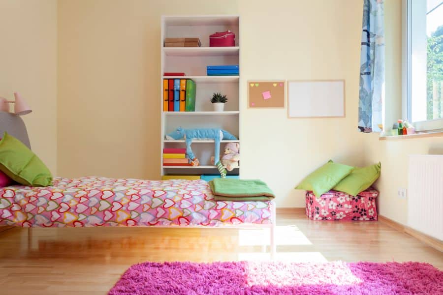 girls bedroom colorful bedspread pink floor rug white shelving unit 