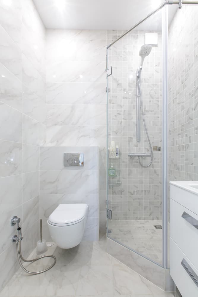white tile bathroom with corner shower and floating toilet 