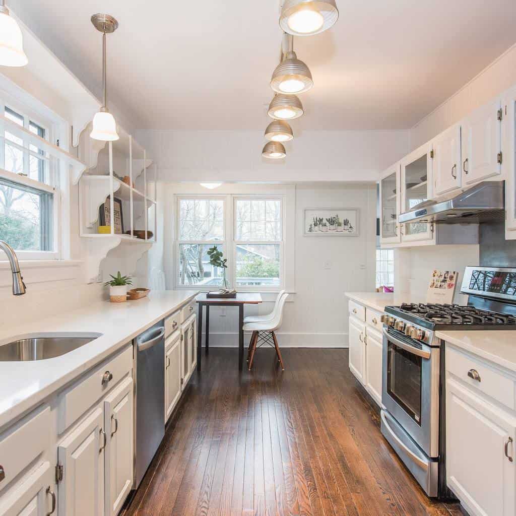 white galley kitchen hardwood floors small table two white chairs 