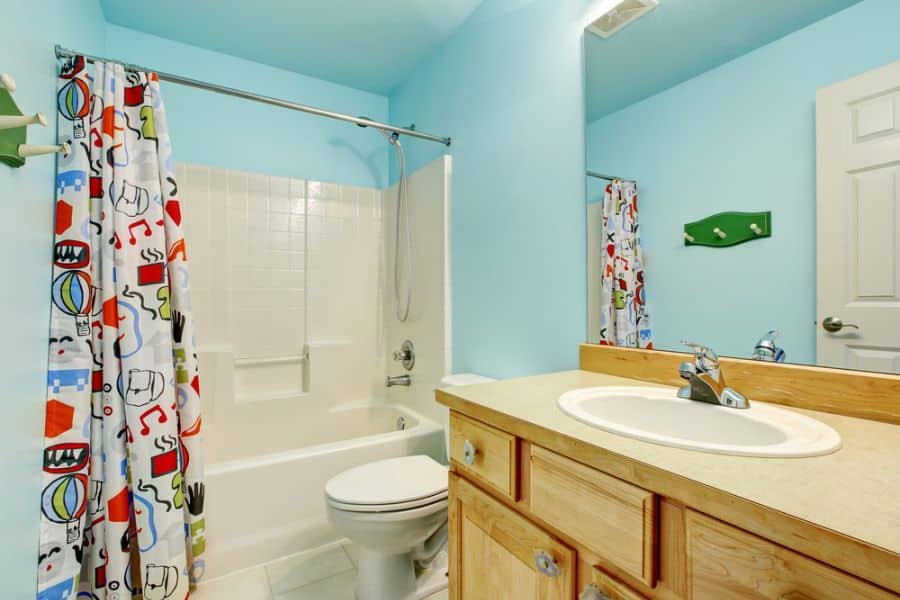 blue wall bathroom white shower tiles wood vanity colorful shower curtain 