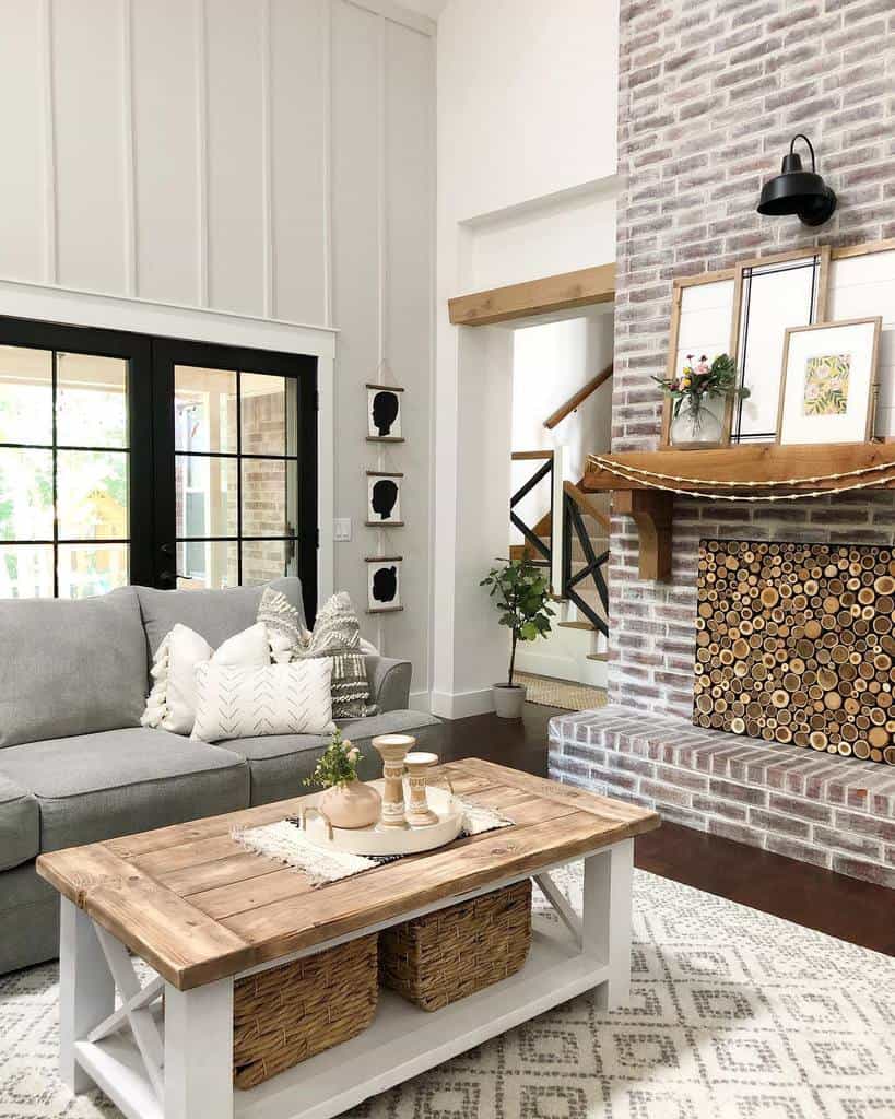 brick fireplace filled with logs wood mantle country style living room wood coffee table gray sofa 