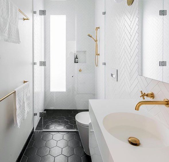 white master bathroom with gold accents and black floor tiles 
