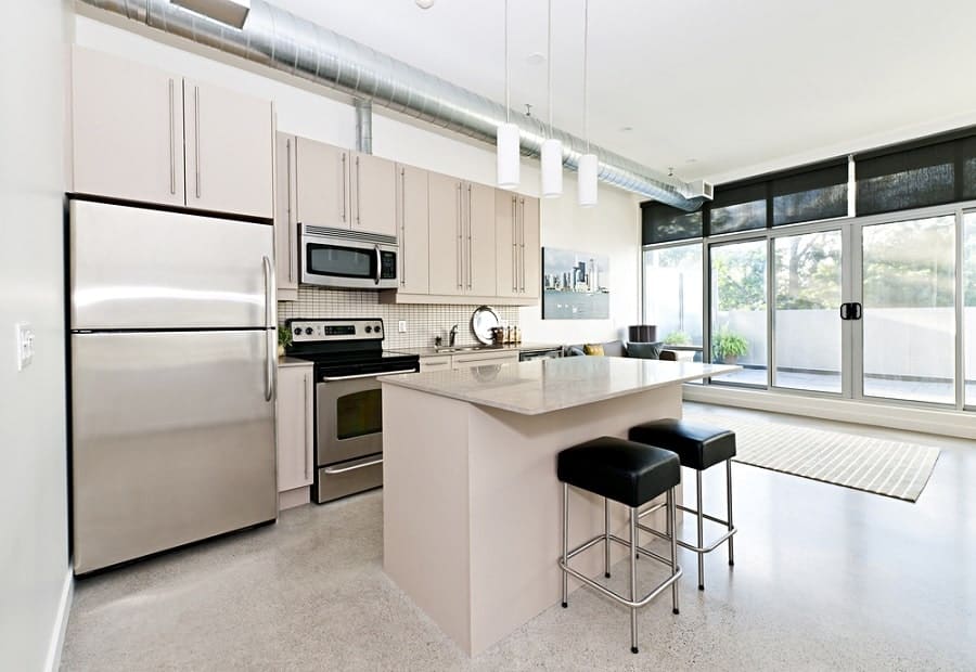 large and bright industrial kitchen with silver appliances and polished cement floor