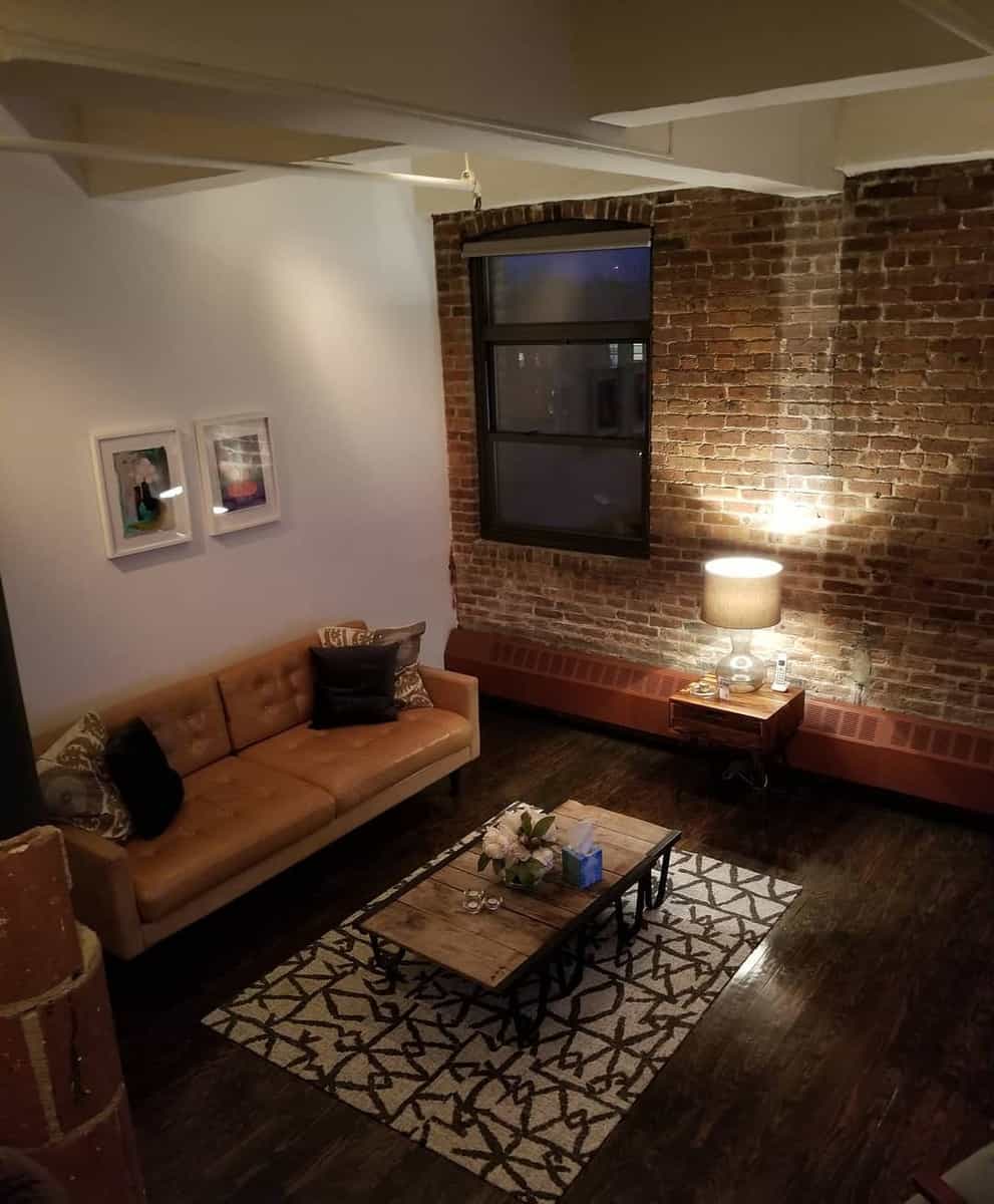 exposed brick wall living room wood floors tan couch