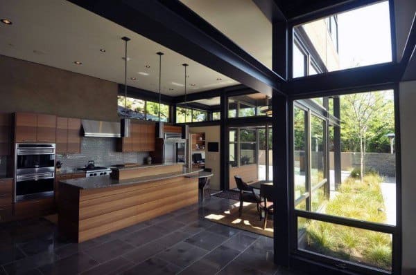 large open brown kitchen with floor to ceiling windows 