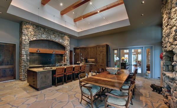 stone kitchen with wood cabinets and large dining table and chairs 