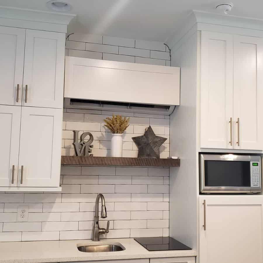 white kitchen cabinets wood floating shelf white tile backsplash 