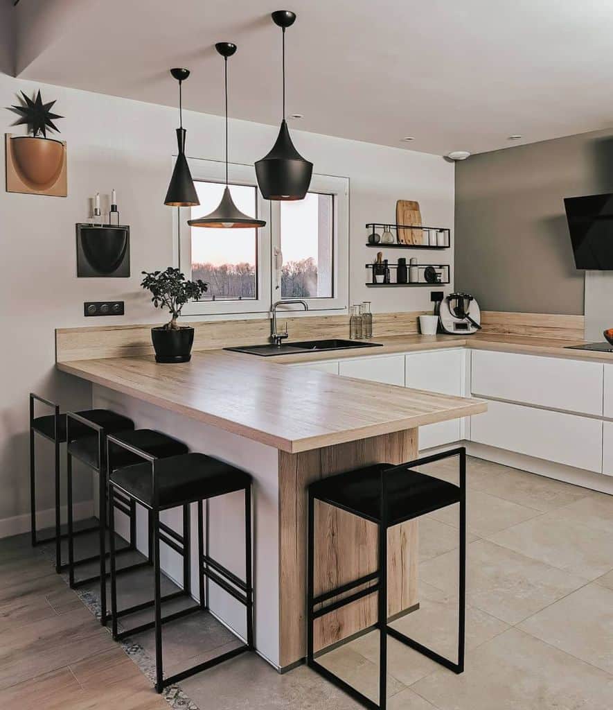 simple modern kitchen white cabinets wood countertop four black chairs pendant lights 