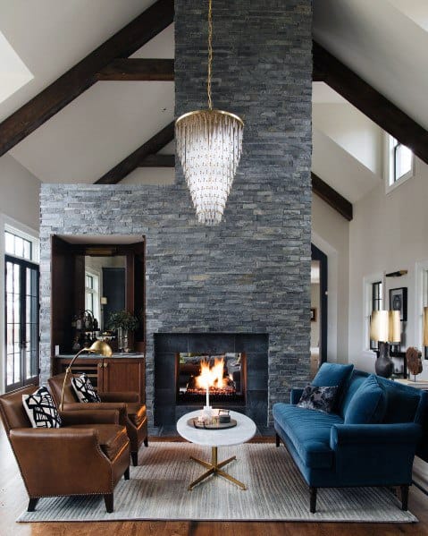 stone fireplace blue sofa brown chairs chandelier
