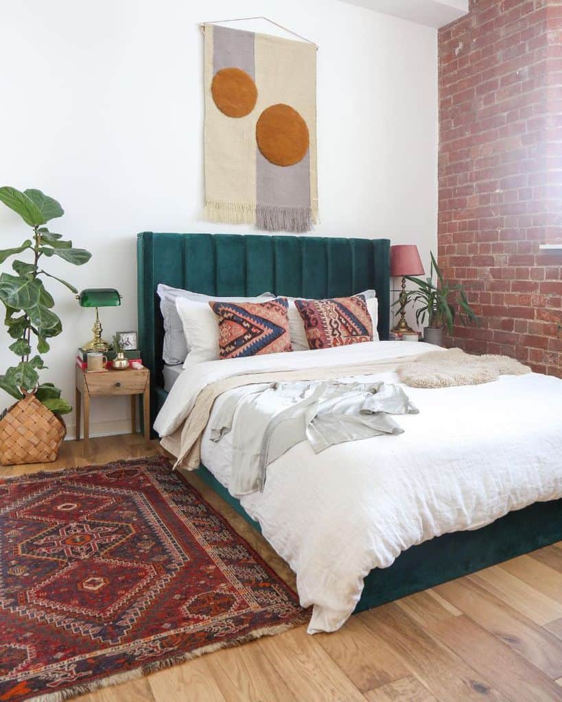 modern boho bedroom exposed brick wall green headboard floor rug