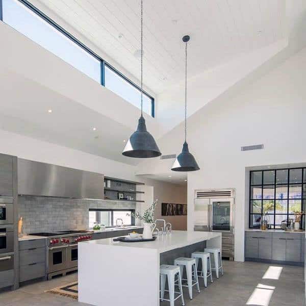 high ceiling kitchen with large white island and breakfast bench white stools concrete floor