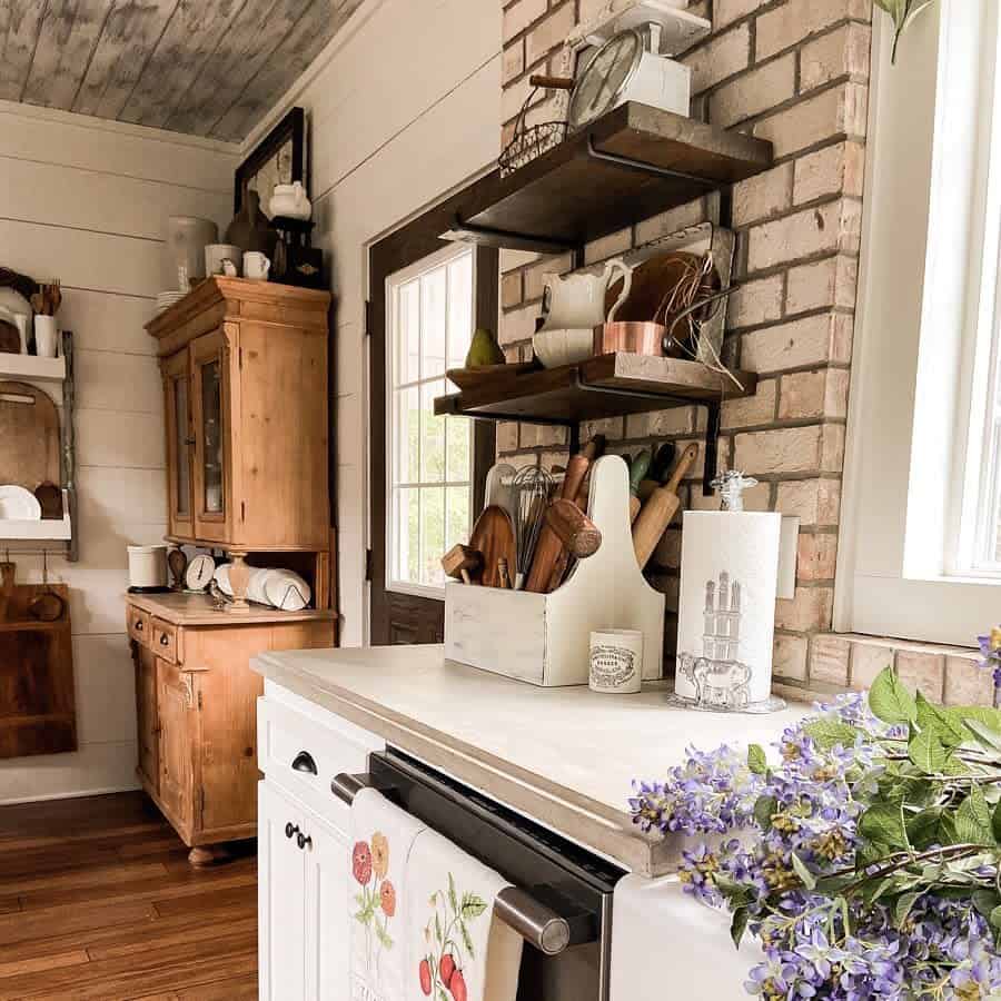 glass paper towel holder in rustic kitchen  with wood cabinets and brick wall