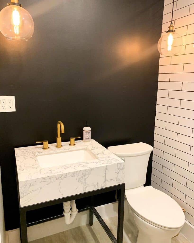 small powder room with black accent wall and white granite sinnk