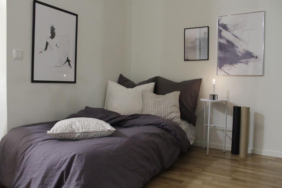 simple bedroom purple bedspread platform bed white bedside table framed artwork 
