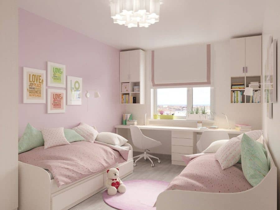 twin beds kids room pink hues white desk and cabinets 