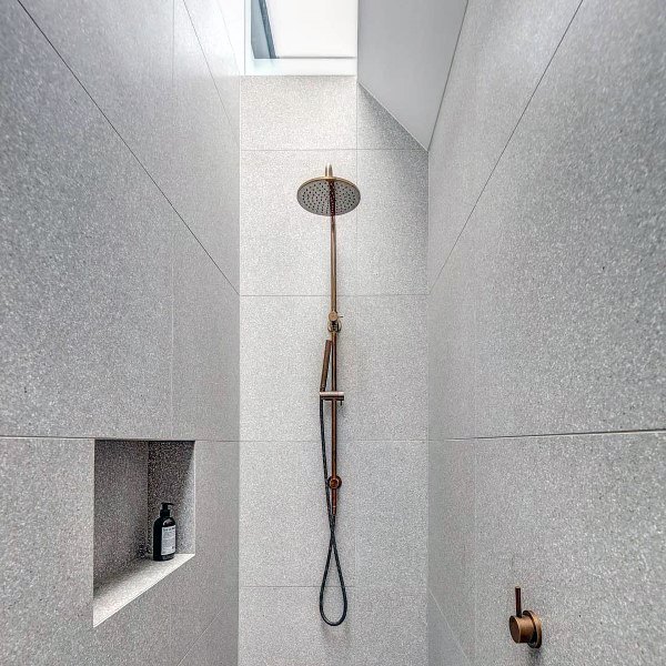narrow modern shower with gold accents 