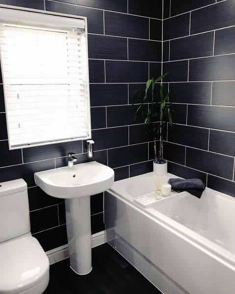 black tile master bathroom with white tub and toilet 
