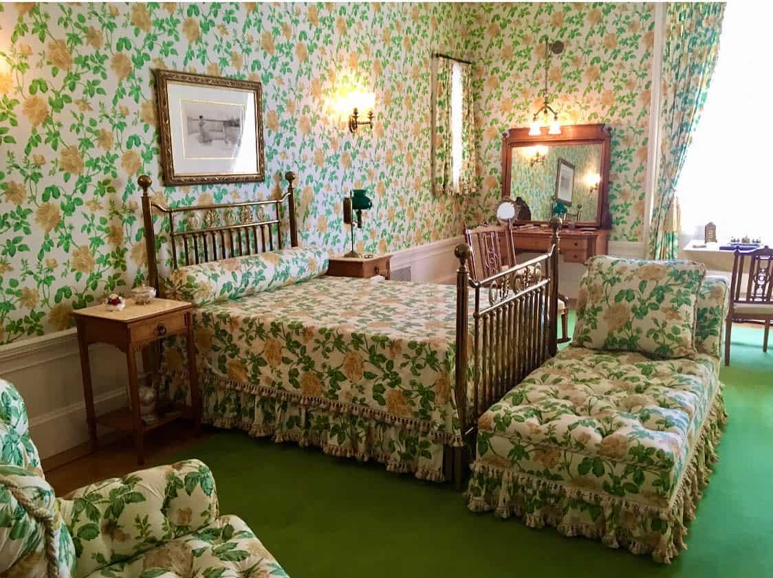 floral green wallpaper bronze bed frame green carpet 