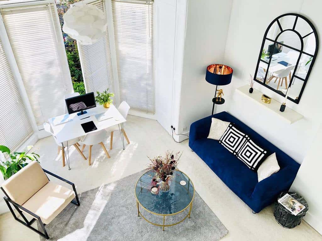 white living room blue sofa glass tabletop white table and four chairs cream and metal accent chair 